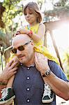 Father and daughter walking outdoors, father carrying daughter on shoulders