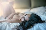 Nude woman lying on bed looking away