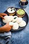 Traditional breakfast with Idli (rice cakes), coriander chutney, coconut chutney and coffee (South India)