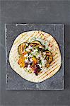 A tortilla wrap with grilled vegetables, feta and tzatziki