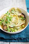 Dumplings in broth with edamame, mushrooms and watercress