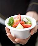 Hand holding a small white ball with mixed fruit salad