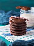 Stack of home made chocolate cookies with red twine over green background