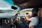 Couple in car, young woman taking photograph through car window, Silverthorne, Colorado, USA