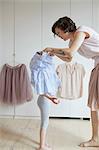 Mother helping daughter to dress