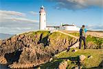 Fanad Head (Fánaid) lighthouse, County Donegal, Ulster region, Ireland, Europe. A photographer on the field near the Fanad Head lighthouse