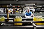 Caucasian male employee working in a bottling plant while wearing a head net.