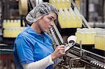 A Caucasian female employee wearing a head net and working on a production line in a bottling plant.