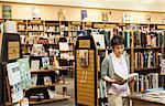 Asian American female browsing through books in a bookstore.