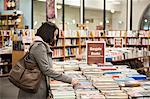 Caucasian female browsing through books in a bookstore.