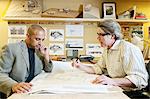 A multi-ethnic team of two male architects working on plans for a new home in an architect's office.