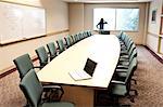 Woman using her phone at a window in a conference room.