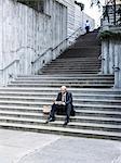 Black businessman taking a break for lunch sitting on a stairway step.