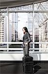 View of a Caucasian business woman in a suit coat standing in a covered glass walkway.