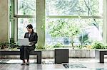 Asian businesswoman working in a large open lobby area.