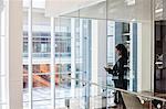 Businesswoman standing in a conference room window in a large business centre.