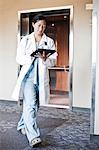 Asian woman doctor walking in a hospital hallway while working on a notebook computer.