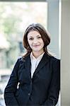 Caucasian business woman in a suit coat standing in an open lobby area.