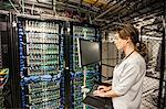 Caucasian woman technician doing diagnostic tests  on computer servers in a server farm.