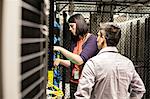 Caucasian woman and man technicians working on CAT 5 cables in a large computer server farm.