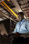 Black man technician doing diagnostic tests  on computer servers in server farm.