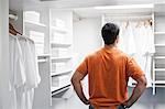 Hispanic man in a closet full of white clothes.