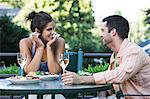Hispanic couple having a healthy meal and a glass of white wine sitting outdoors.