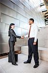 Black businessman and Hispanic businesswoman in the lobby of a large office building.