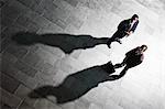 View from above of two businessmen and shadows on the floor of a business lobby.