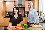 Asian man and woman preparing fresh vegetables in their kitchen.