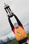 Caucasian man celebrating a sporting event win with a trophy.