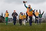 Team members celebrating a victory and a trophy in an outdoor sporting event in the winter.