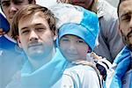 Father and son watching football match, portrait