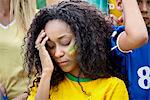 Woman holding head in disappointment at Brazilian football match
