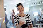 Portrait smiling, confident creative businesswoman using digital tablet in office