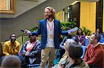 Smiling male speaker with microphone talking to conference audience