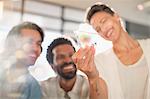 Smiling, curious, innovative entrepreneurs examining glass triangle prototype