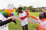 Playful runners celebrating, throwing holi powder at charity run in park