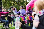 Female runners high-fiving spectators at charity run finish line