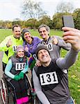 Man in wheelchair taking selfie with friends at charity race in park