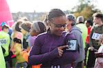 Female runner preparing music on mp3 player arm band at charity run