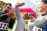 Happy runner friends taking selfie with camera phone at charity run in park