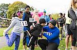 Family runners preparing, stretching at charity run in park