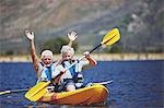 Playful, energetic active senior couple kayaking on sunny summer lake