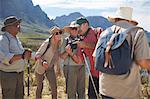 Active senior friends with digital camera hiking with hiking poles