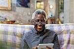 Smiling senior man using digital tablet on sofa