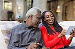 Adult daughter showing senior father how to use digital tablet