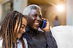 Happy grandfather and granddaughter talking on cell phone