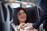 Smiling woman with smart phone using contactless payment on passenger train