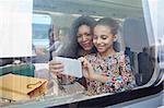 Mother and daughter using camera phone at window of passenger train